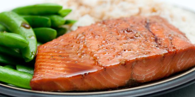 a baked salmon with soy-based glaze, served with snap peas and white rice